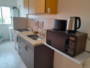 a small kitchen with a microwave and a sink at Depto Rawson Home in Rawson