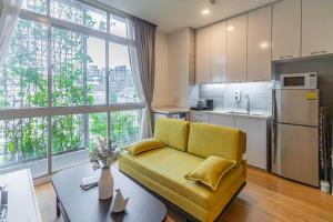 a living room with a yellow couch and a kitchen at Thanksgiving Serviced Residence in Singapore
