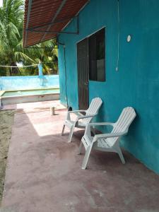 two white chairs and a table next to a blue building at casa en playa santa clara yucatan in Santa Clara