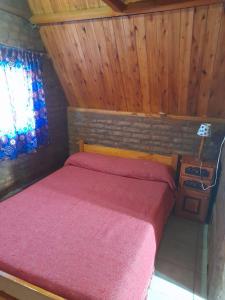 sypialnia z czerwonym łóżkiem i oknem w obiekcie El Cristal w mieście Puerto Pirámides