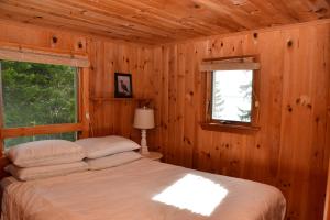 a bedroom with a bed and a window in a cabin at Betty's Place - Cozy ocean front getaway with views of Casco Bay in Orrs Island