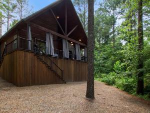 a house in the middle of the forest at Stunning Luxury Cabin w Hot Tub and Fire Pit Holy Shiplap is Perfect Romantic Couples Getaway in Broken Bow