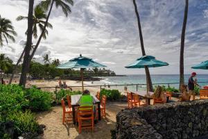a group of people sitting at a table with umbrellas on the beach at Amazing Oceanfront Condo w/ Breath Taking Sunsets and Soothing Sea Breeze! - Hale Kona Kai 306 in Kailua-Kona +12 photos