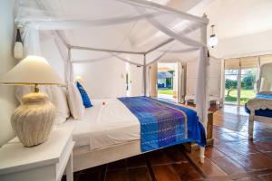 a bedroom with a canopy bed and a table with a lamp at Villa Nirvana Biru Bingin Beach in Uluwatu