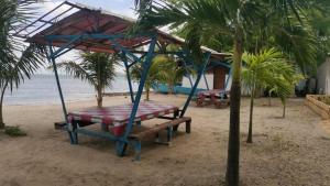 una mesa de picnic y un columpio en una playa en Binubusan Beach Hotel and Resort en Lian