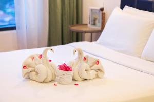 Tres cisnes hechos de toallas en una cama en Tropicana 218 Macalister X Airlevate Suites, en George Town