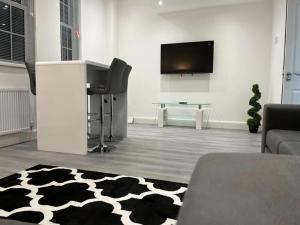 - un salon avec une télévision et un tapis noir et blanc dans l'établissement Watford City Centre Retreat - Spacious Modern Self-Contained Apartment - Sleeps 4, à Watford