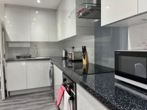 cocina con armarios blancos y encimera negra en SPACIOUS & MODERN 1 bed CITY CENTRE Apartment, en Watford