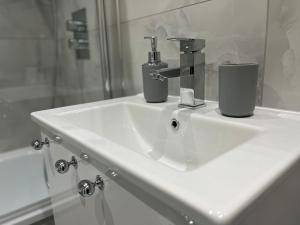 a bathroom sink with two cups on top of it at SPACIOUS & MODERN 1 bed CITY CENTRE Apartment in Watford