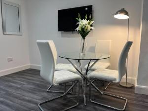 einen Glastisch mit Stühlen und eine Vase aus Blumen in der Unterkunft Spacious & Modern CENTRAL 1 bed Apartment with OUTSIDE space in Watford