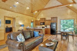 a living room with a couch and a kitchen at Gorgeous Idyllic Cabin w Hot Tub and Fire Pit Quittin Time is Secluded Romantic Oasis w Luxury Bathroom Double Shower and Bathtub Foosball Table in Broken Bow