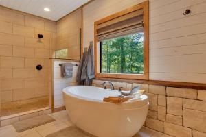 a large bathroom with a tub and a window at Gorgeous Idyllic Cabin w Hot Tub and Fire Pit Quittin Time is Secluded Romantic Oasis w Luxury Bathroom Double Shower and Bathtub Foosball Table in Broken Bow +32 photos
