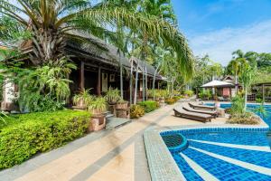 a resort with a swimming pool and palm trees at Botany Beach Resort in Na Jomtien