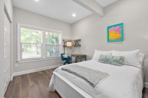 a white bedroom with a bed and a window at Oneida Charmed - Historic Cottage w Modern Flair in Saint Augustine