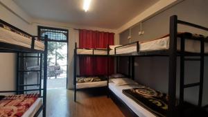 a room with three bunk beds and a window at Thrillomania Mcleodganj in Dharamshala