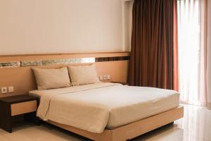 a bed in a hotel room with a large window at Lembah Permai Resort in Sindanglaya