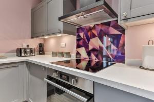 a kitchen with white cabinets and a stove top oven at Luxury Spacious Pad with Games Room in Sheffield