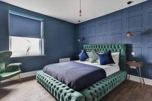 a bedroom with a large bed with a green tufted headboard at Luxury Spacious Pad with Games Room in Sheffield