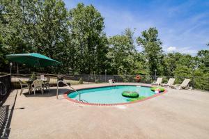 a swimming pool with an umbrella and a table and chairs at Cabin in the woods WIFI, 1 story in Eureka Springs