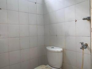 W wyłożonej białymi kafelkami łazience znajduje się toaleta. w obiekcie SPOT ON 92547 Wisma Dg Tata w mieście Makasar