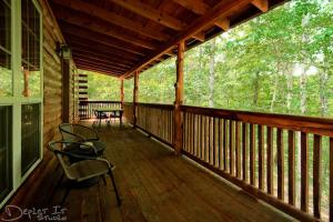 Un porche de una cabaña con una mesa y sillas. en Secluded 2 story cabin Pool WiFi smart TVs, en Eureka Springs