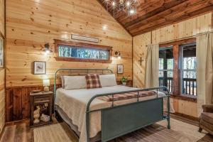 a bedroom with a bed in a room with wooden walls at Large Luxury 2BR Cabin w Hot Tub Double Trouble was designed for fun comfort and memories minutes from buzzling Hochatown and beautiful Beaver Bend State Park in Broken Bow