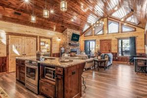 a kitchen with an island in a room with wooden walls at Large Luxury 2BR Cabin w Hot Tub Double Trouble was designed for fun comfort and memories minutes from buzzling Hochatown and beautiful Beaver Bend State Park in Broken Bow