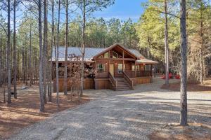 a large log cabin in the woods with a driveway at Large Luxury 2BR Cabin w Hot Tub Double Trouble was designed for fun comfort and memories minutes from buzzling Hochatown and beautiful Beaver Bend State Park in Broken Bow