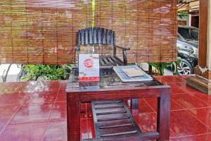 een houten tafel met een stoel op een patio bij OYO 92560 Astri Homestay in Tjakranegara