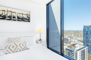 a bedroom with a white bed and a large window at Elegant and Cozy Top Floor 1BD Apartment at South Bank in Brisbane +24 photos