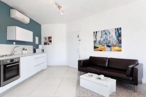 a living room with a black couch and a kitchen at Beautiful Studio in Flea Market By Holiday Rentals in Tel Aviv