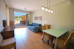 - un salon avec une table, des chaises et un canapé dans l'établissement Apartamentos Nova Denia - Deniasol, à Dénia