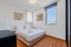 a white bedroom with a large bed and a window at 2BR - 2 12 Hei be-Iyar St Tel aviv in Tel Aviv