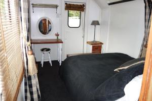 a bedroom with a bed and a mirror and a table at Tiny House Train-Eco stay in Upper Hutt
