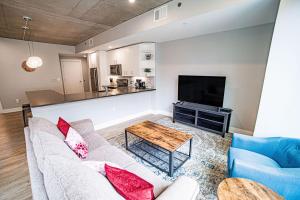 ein Wohnzimmer mit einem Sofa, einem Tisch und einem TV in der Unterkunft Modern 2 BR with Balcony in GR Entertainment District in Grand Rapids