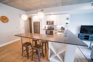 a kitchen with a large counter with stools in it at Modern 2 BR with Balcony in GR Entertainment District in Grand Rapids