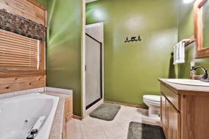 baño verde con bañera, aseo y lavamanos en Secluded Cabin in the Woods! 1 story, en Eureka Springs