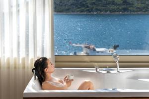 a woman sitting in a bath tub with a cup of coffee at Liman Hotel Gümüslük - Adult Only in Bodrum City +37 photos