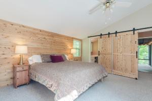 a bedroom with a bed and a wooden wall at Secluded Oasis w Hot Tub, Screened-in Porch, WiFi! in Berkeley Springs