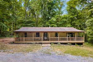 una casa en el bosque con un gran porche en Modern Cabin w Hot Tub Fire Pit WiFi, en Berkeley Springs