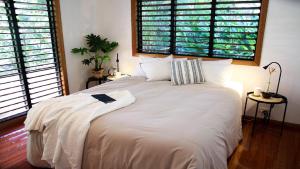 Un dormitorio con una gran cama blanca con dos ventanas. en Picnic House, Luxurious Tropical House, en Picnic Bay