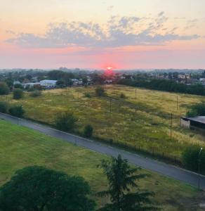 einen Sonnenuntergang über einem Feld mit einer Straße in der Unterkunft AMANECER Rent Apart - Tú Hogar! Amplio y Luminoso con Desayuno in Junín