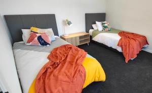 a bedroom with two beds and a table with a lamp at Historic Inner City Apartment in Invercargill +2 photos