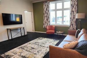 sala de estar con sofá y TV en Historic Inner City Apartment en Invercargill