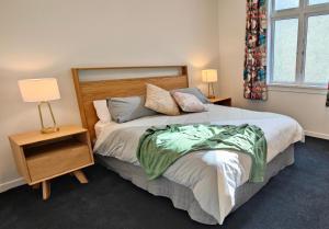 ein Schlafzimmer mit einem Bett, zwei Lampen und einem Fenster in der Unterkunft Historic Inner City Apartment in Invercargill