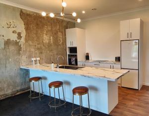 una cocina con una gran isla con taburetes de bar en Historic Inner City Apartment en Invercargill