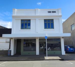 a white building with a sign on it at Historic Inner City Apartment in Invercargill