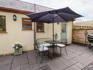a patio with a table and chairs and an umbrella at Number 10 Puffin Cottage in Camelford
