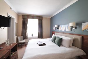 a bedroom with a large white bed and a window at The White Lion Hotel in Aldeburgh