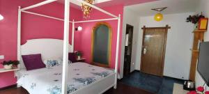 um quarto com uma cama de dossel branca numa parede cor-de-rosa em Zhangjiajie April Hostel em Zhangjiajie